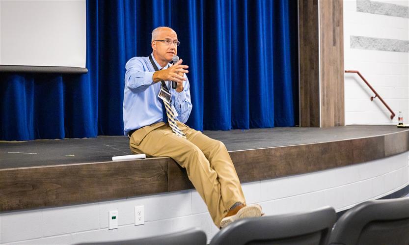 Superintendent Jason Golden sits on edge of stage